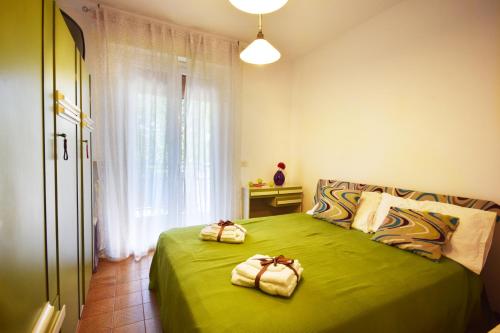 een slaapkamer met een groen bed met 2 handdoeken erop bij Appartamento viale pedonale a due passi dal mare in Bellaria-Igea Marina