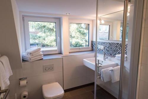 ヴェスターラントにあるMeeresrauschen-Landhaus-Tadsenのバスルーム(洗面台、トイレ付)、窓2つが備わります。