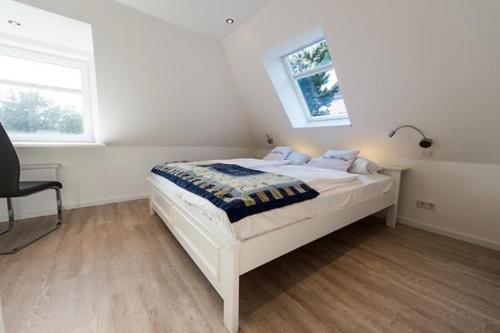 Schlafzimmer mit einem Bett, einem Schreibtisch und einem Fenster in der Unterkunft Meeresrauschen - Landhaus Tadsen in Westerland