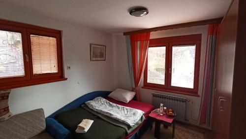 a small room with a bed and two windows at Cozy room with a bathroom in Sarajevo