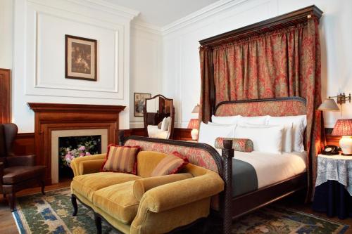 a bedroom with a bed and a chair and a fireplace at The Ned in London