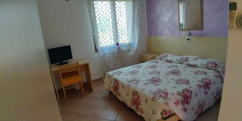 a bedroom with a bed and a desk with a television at Agriturismo La Fraterna in Tolle