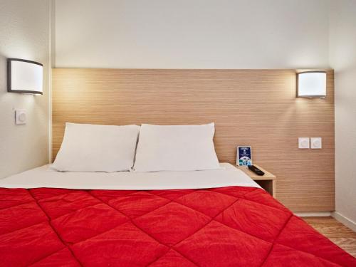sypialnia z dużym łóżkiem i czerwonym kocem w obiekcie Premiere Classe Cergy Saint Christophe w mieście Cergy