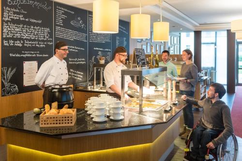 een groep mensen die achter een balie in een restaurant staan bij euvea Freizeit- und Tagungshotel in Neuerburg