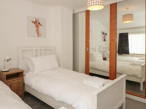 a bedroom with two beds and a mirror at George Cottage in Dartmouth