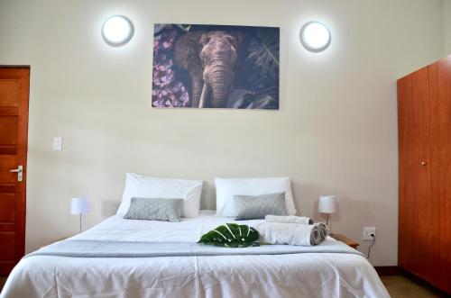a bedroom with a bed with an elephant picture on the wall at Muqurati Lodge - Dinokeng Game Reserve in Klipdrift