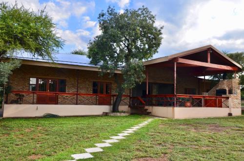 a house with a tree in front of it at Muqurati Lodge - Dinokeng Game Reserve in Klipdrift