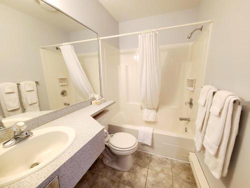a white bathroom with a sink and a toilet at Horizon 777 in Saint-Siméon