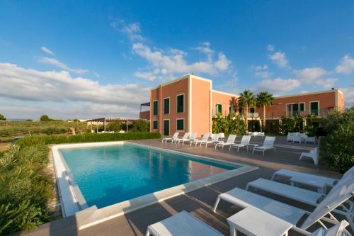 a swimming pool with white chairs and a building at Corte Olea Resort in Paceco