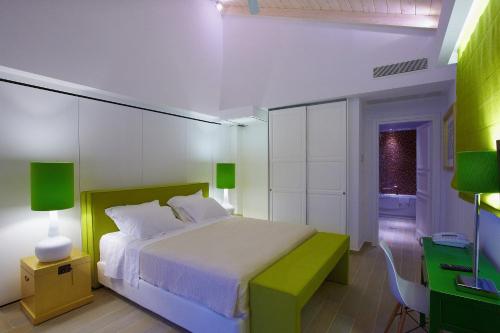 a bedroom with a white bed and a green bench at Salvator Villas & Spa Hotel in Parga