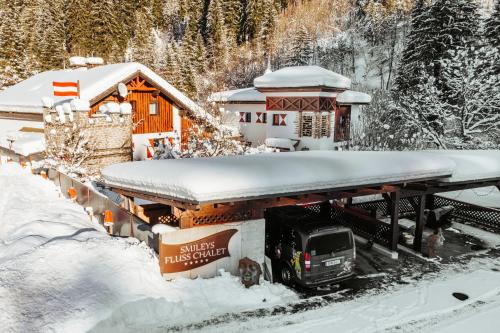 a truck parked next to a house in the snow at Smileys Fluss Chalet in Trebesing