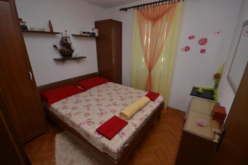 um pequeno quarto com uma cama com lençóis vermelhos em Apartment Vila Punta 4234 em Splitska