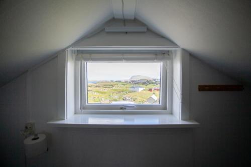 a bathroom window with a view of a field at Red Robin - Vacation homes next to Svartifossur waterfall in Tórshavn