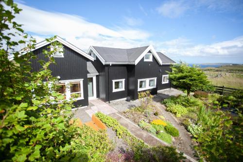 a black house with a garden in front of it at Red Robin - Vacation homes next to Svartifossur waterfall in Tórshavn