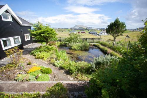 un jardín frente a una casa con un arroyo en Red Robin - Vacation homes next to Svartifossur waterfall, en Tórshavn