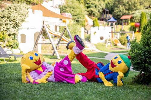 two cartoon characters laying on the grass in a park at Smileys Fluss Chalet in Trebesing