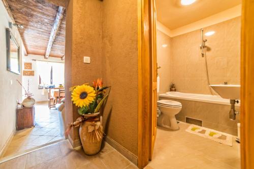 a bathroom with a toilet and a sink and a vase of flowers at Holiday House Eleonora in Barban