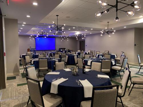 a banquet hall with tables and chairs and a screen at Cambria Hotel St Petersburg-Madeira Beach Marina in St Pete Beach