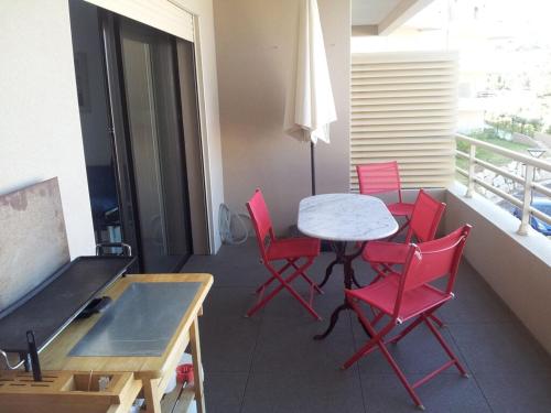 a room with a table and red chairs and a balcony at Jardins de Quatrina in Propriano