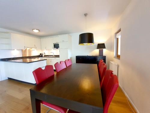 a kitchen with a dining table and red chairs at Walensee House & Apartments in Unterterzen
