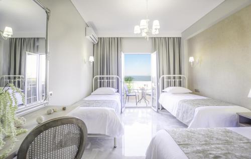 a hotel room with three beds and a view of the ocean at Erofili Hotel in Kavos