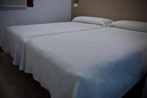 two beds in a room with white sheets at Pension Norte in Portugalete