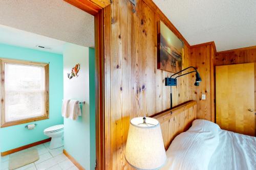 a bedroom with a wooden wall with a bed and a toilet at Three Sheets to the Wind #70-1 in Avon