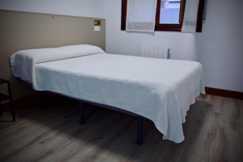 a bed in a room with white sheets on it at Pension Norte in Portugalete