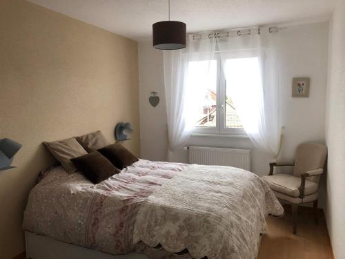 een slaapkamer met een bed, een raam en een stoel bij Au pied des Vosges in Obernai