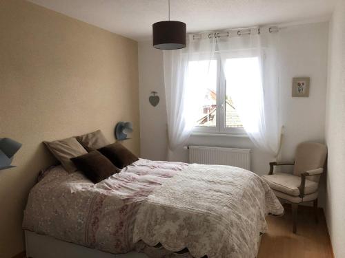 a bedroom with a bed and a window and a chair at Au pied des Vosges in Obernai