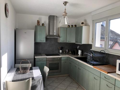 une cuisine avec des armoires vertes et une table avec une table dans l'établissement Au pied des Vosges, à Obernai