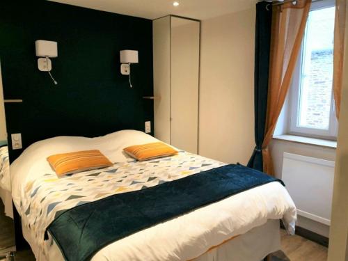 1 dormitorio con 1 cama grande con almohadas de color naranja en Port de La Houle - Beau 2 pièces classé 3 étoiles avec stationnement en Cancale