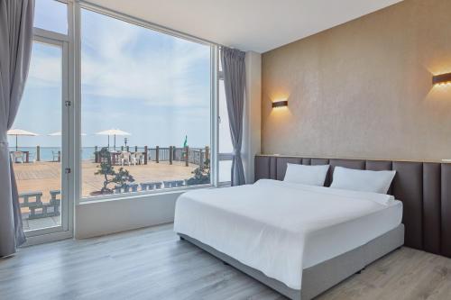 a bedroom with a large white bed and a large window at Ferry of Love Homestay in Shimen