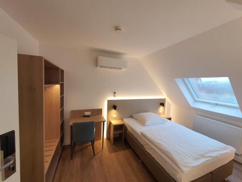 a bedroom with a bed and a desk and a window at Hotel zur Traube in Möglingen