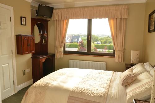 a bedroom with a bed and a large window at Dunross House B&B in Killarney