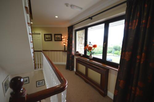 a hallway with a staircase and a window with a vase of flowers at Dunross House B&B in Killarney