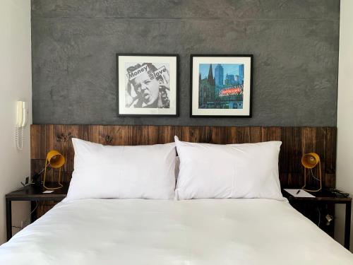 a bedroom with a white bed with three pictures on the wall at Ayacucho apartments near Huaca Pucllana in Lima