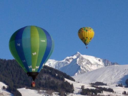 two hot air balloons flying over a snow covered mountain at L'esquirot in Megève