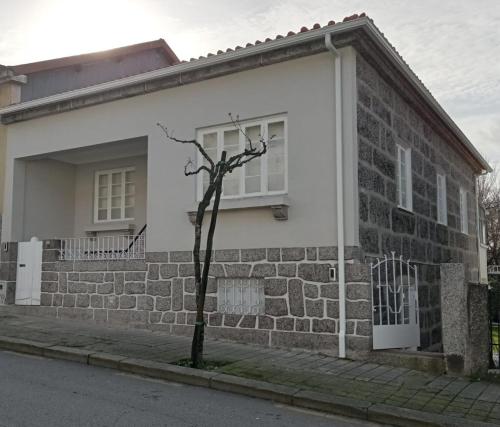 a small tree in front of a brick house at 4-As Moradias Centro in Guimarães