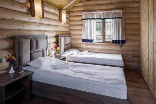 two beds in a wooden room with a window at Grig House Eco Resort in Gyulagarak