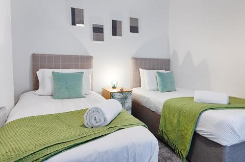 Habitación con 2 camas y sábanas verdes y blancas. en Pleasant Hill - TV in every Bedroom! en Swansea