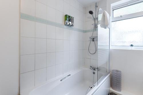 een witte badkamer met een bad en een raam bij Pleasant Hill - TV in every Bedroom! in Swansea