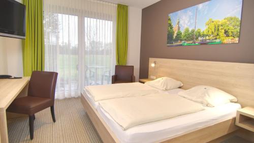 - une chambre avec un lit, un bureau et une fenêtre dans l'établissement Hotel Heilemann, à Wietmarschen