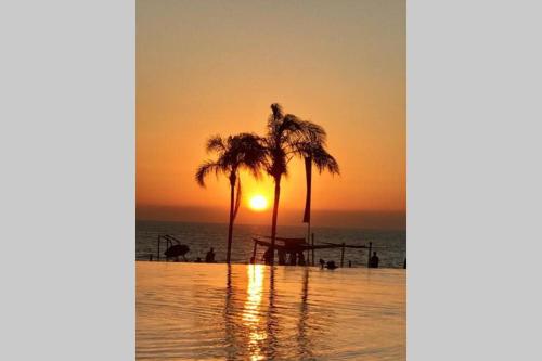 a sunset on a beach with palm trees and the ocean at De las mejores vistas del Condominio in Nuevo Vallarta 