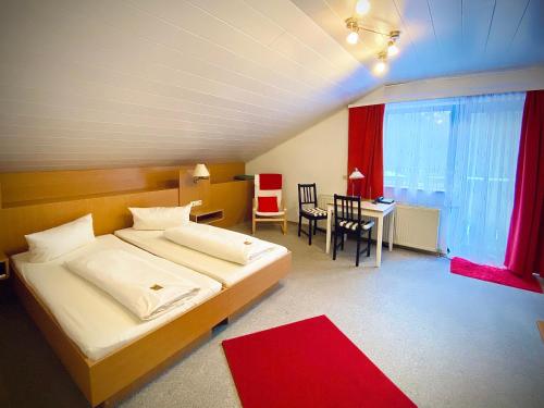 um quarto com uma cama grande e uma mesa com um tapete vermelho em Meister BÄR HOTEL Am Wald em Marktredwitz