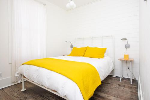 a white bedroom with a yellow blanket on a bed at South Main Residences by Surf Hotel in Buena Vista