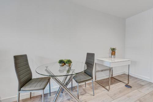 a glass table with four chairs and a white table at St Martins 2 Bedroom Apartments in Ruislip By 360 Stays in Ruislip