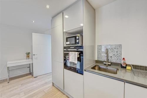 a kitchen with white cabinets and a sink at St Martins 2 Bedroom Apartments in Ruislip By 360 Stays in Ruislip
