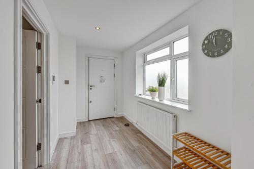 an empty hallway with white walls and a clock on the wall at St Martins 2 Bedroom Apartments in Ruislip By 360 Stays in Ruislip
