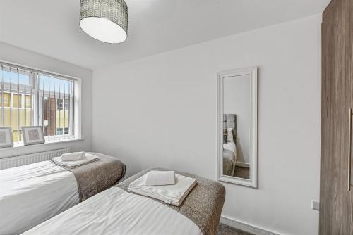 a white bedroom with two beds and a mirror at St Martins 2 Bedroom Apartments in Ruislip By 360 Stays in Ruislip